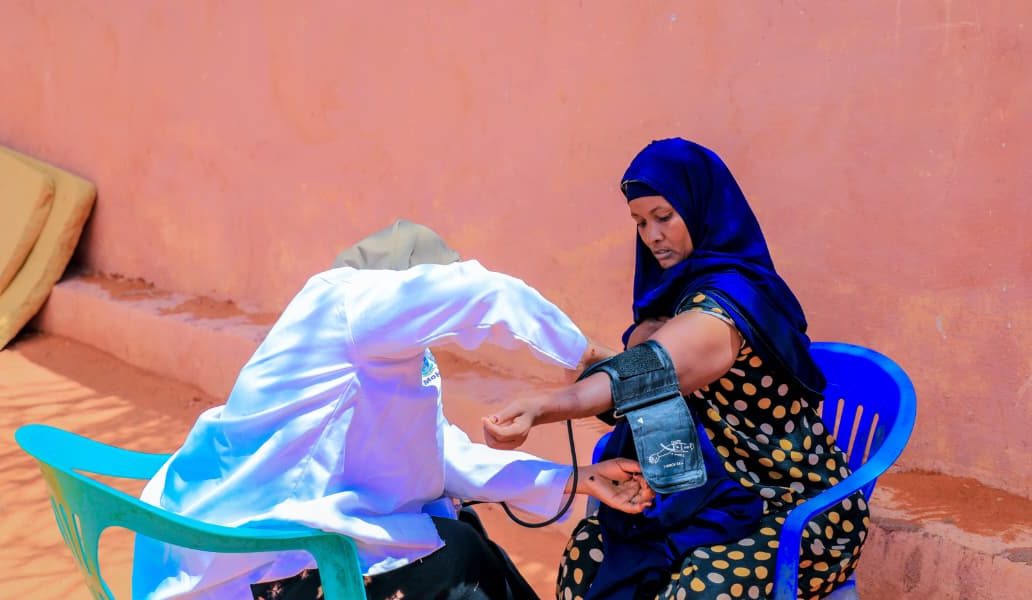 A Rajo clinician checking a woman's blood pressure at a community outreach assessment in Galdogob